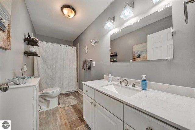bathroom featuring vanity, wood finished floors, toilet, baseboards, and a shower with shower curtain