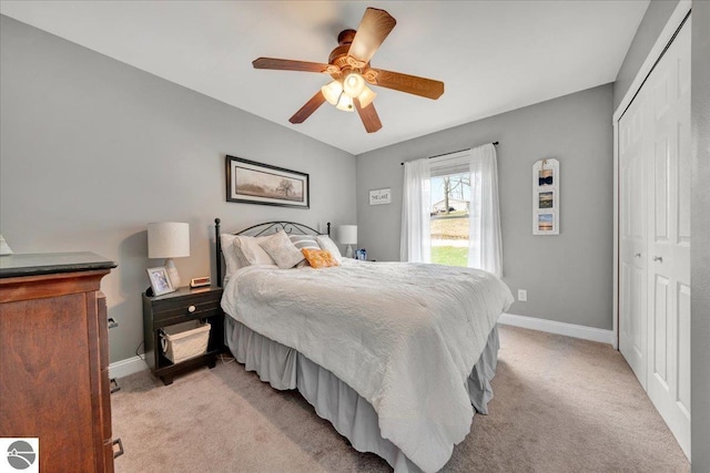 bedroom with a ceiling fan, baseboards, light carpet, and a closet