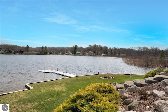 view of dock with a yard and a water view