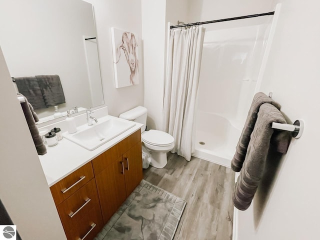 bathroom featuring vanity, a stall shower, wood finished floors, and toilet