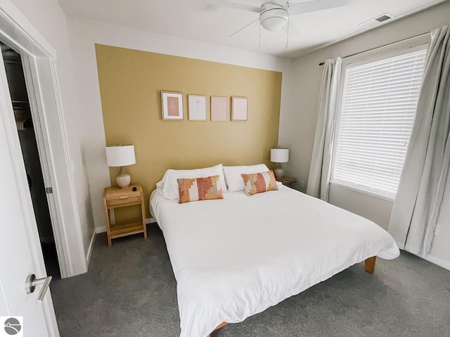 bedroom with multiple windows, dark colored carpet, and visible vents