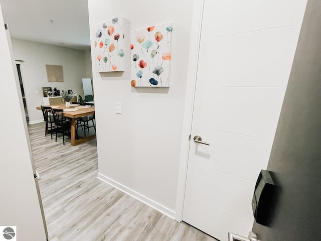 corridor featuring baseboards and light wood finished floors