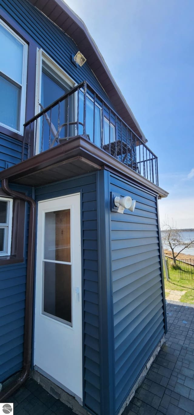 view of property exterior featuring a water view, a patio area, and a balcony