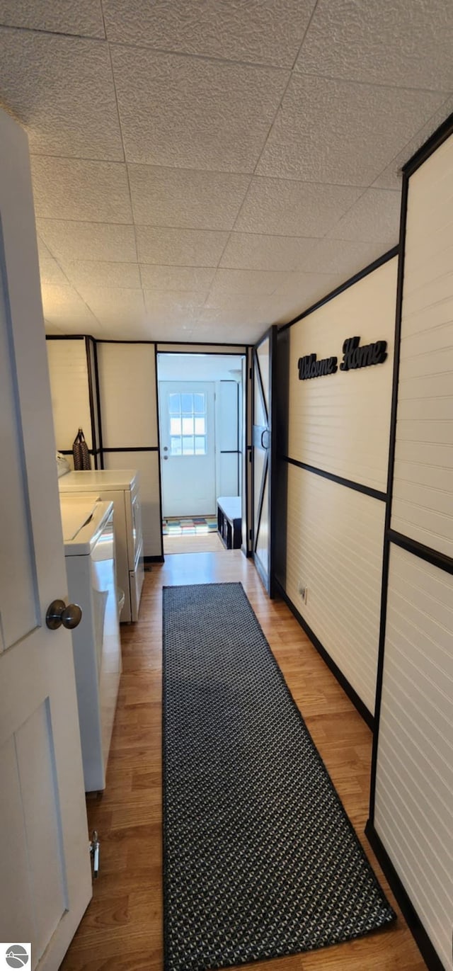 hall featuring baseboards, wood finished floors, and washer and clothes dryer