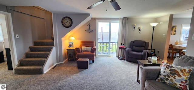 carpeted living area featuring baseboards, a ceiling fan, and stairs