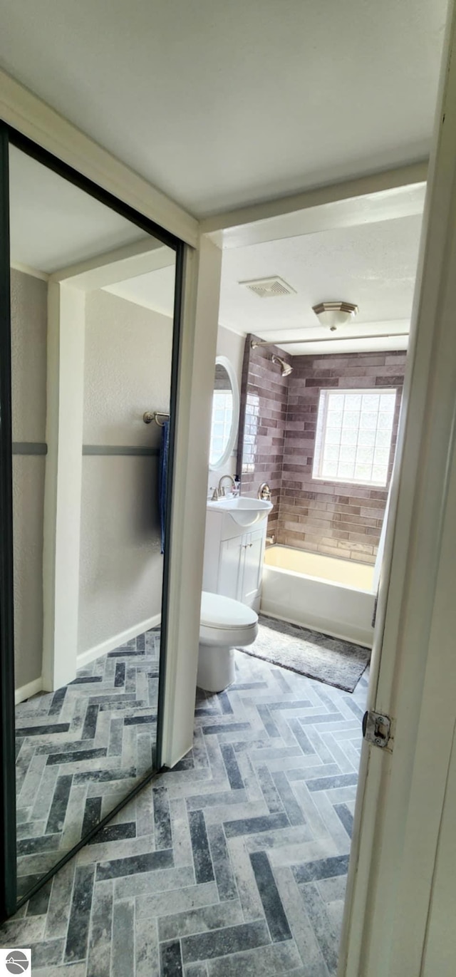 bathroom featuring vanity, toilet, visible vents, and bathtub / shower combination