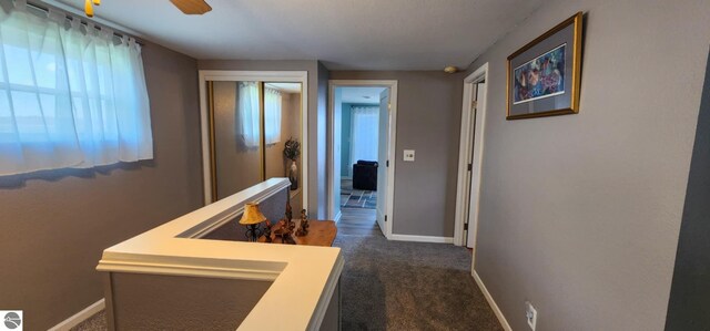 corridor with dark carpet and baseboards