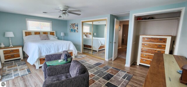bedroom featuring two closets, baseboards, ceiling fan, and wood finished floors