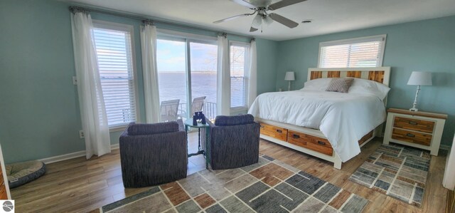 bedroom featuring a water view, multiple windows, and wood finished floors