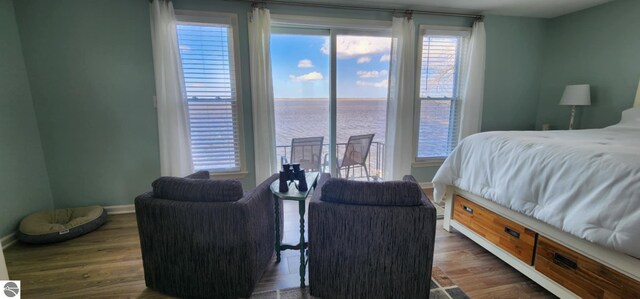 bedroom with a water view, baseboards, and wood finished floors