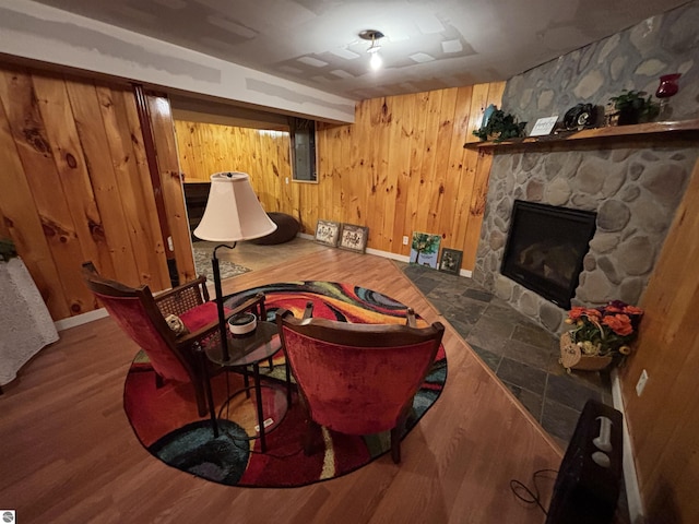 3633 Driftwood Dr, Cadillac, MI 49601 - living area featuring baseboards, wood walls, a stone fireplace, and wood finished floors