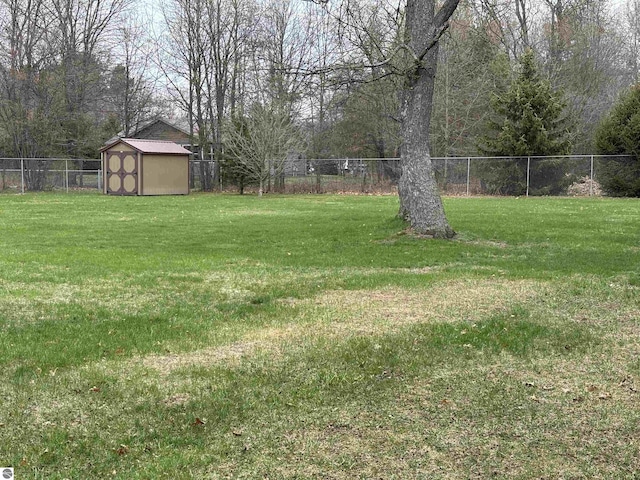 3633 Driftwood Dr, Cadillac, MI 49601 - view of yard featuring a storage unit, a fenced backyard, and an outbuilding