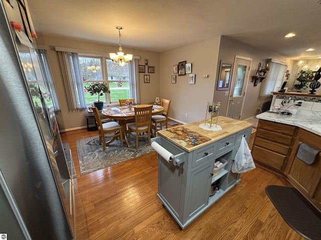 3633 Driftwood Dr, Cadillac, MI 49601 - kitchen featuring an inviting chandelier, gray cabinetry, wood finished floors, and decorative light fixtures