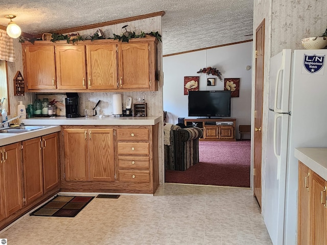 kitchen with freestanding refrigerator, a textured ceiling, crown molding, and light countertops