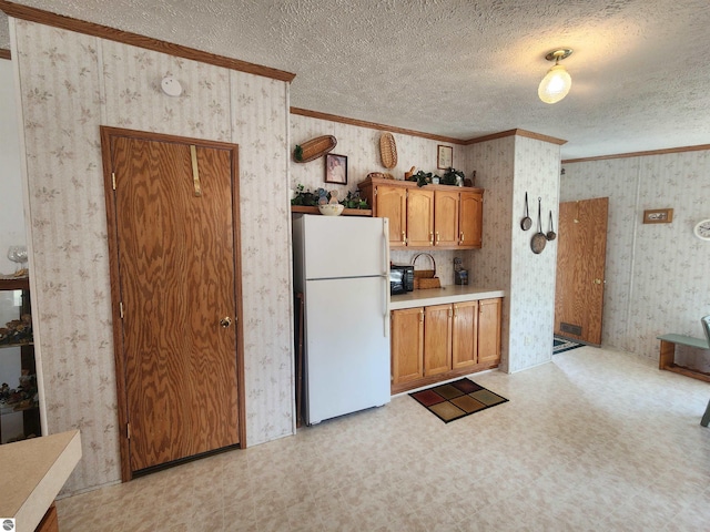 kitchen featuring wallpapered walls, freestanding refrigerator, light floors, and ornamental molding