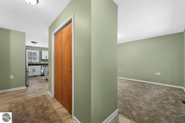 4326 Antioch Dr, Mesick, MI 49668 - hallway with baseboards, a sink, and light wood-style flooring