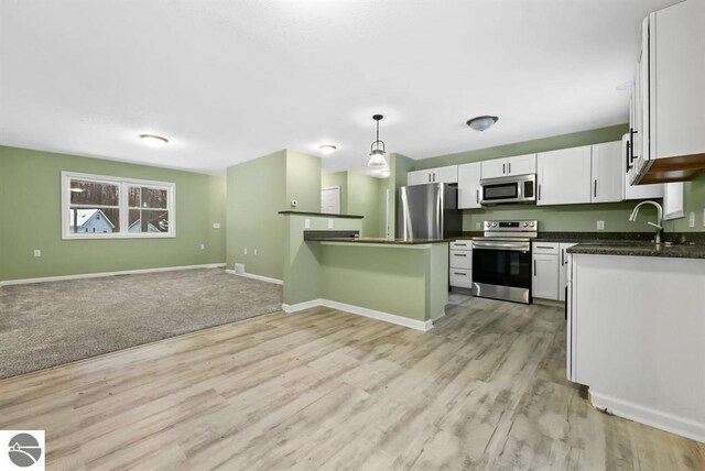 4326 Antioch Dr, Mesick, MI 49668 - kitchen featuring dark countertops, appliances with stainless steel finishes, white cabinets, open floor plan, and light wood-style floors