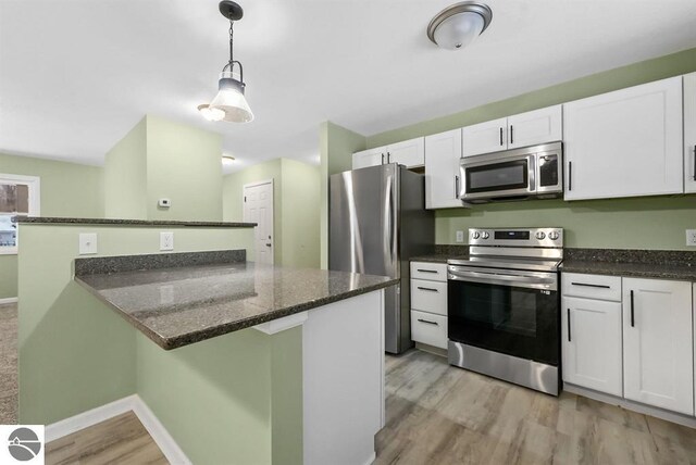 4326 Antioch Dr, Mesick, MI 49668 - kitchen with pendant lighting, white cabinetry, light wood finished floors, and stainless steel appliances