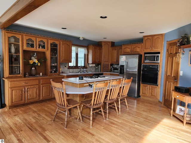 1697 Wildwood Rd, Sterling, MI 48659 - kitchen with appliances with stainless steel finishes, brown cabinetry, a breakfast bar, and light wood-style floors