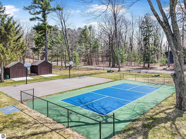 view of property's community with a tennis court, fence, and a shed