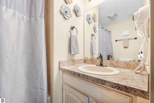 bathroom with visible vents, a textured ceiling, curtained shower, and vanity
