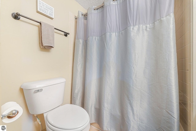 bathroom with a textured ceiling, toilet, and a shower with curtain