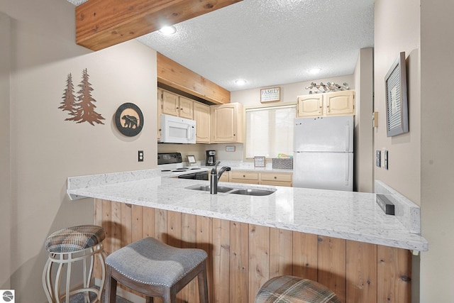 kitchen featuring white appliances, a peninsula, a textured ceiling, and a sink
