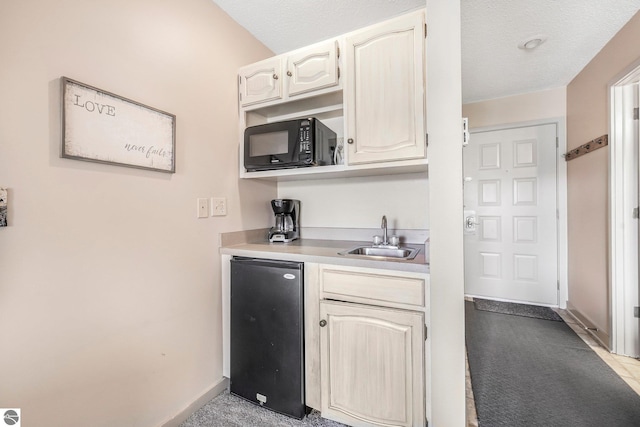 kitchen featuring black microwave, fridge, baseboards, light countertops, and a sink