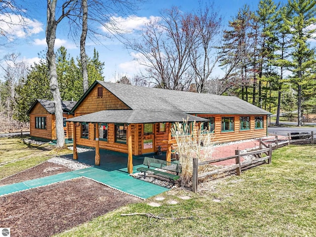 rear view of house featuring a shingled roof, fence, a yard, and log exterior