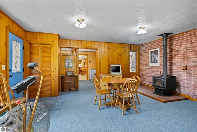 carpeted dining room featuring wooden walls and a wood stove