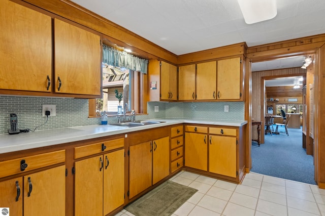 kitchen with light countertops, light tile patterned flooring, decorative backsplash, and a sink
