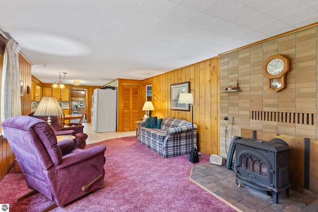 living area featuring wooden walls, light carpet, and a wood stove