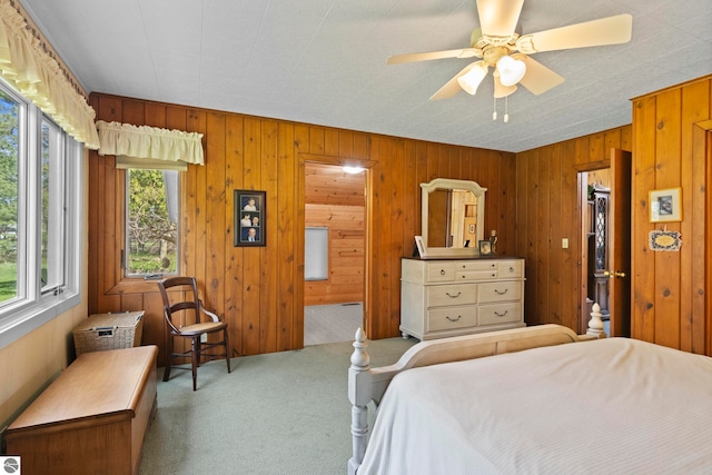 carpeted bedroom with wood walls and a ceiling fan