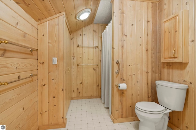 bathroom featuring wooden walls, tile patterned floors, vaulted ceiling, and toilet