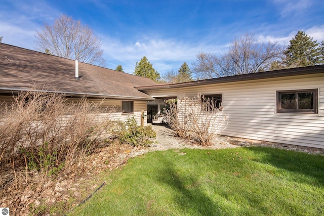 exterior space featuring a lawn and roof with shingles