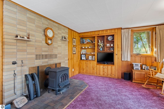 carpeted living room featuring wooden walls and a wood stove