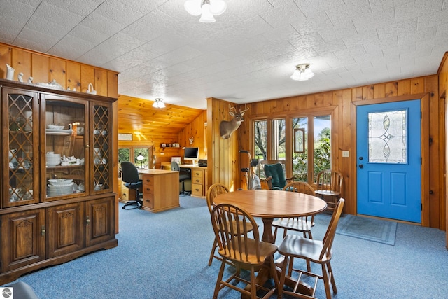 dining area with carpet floors and wooden walls