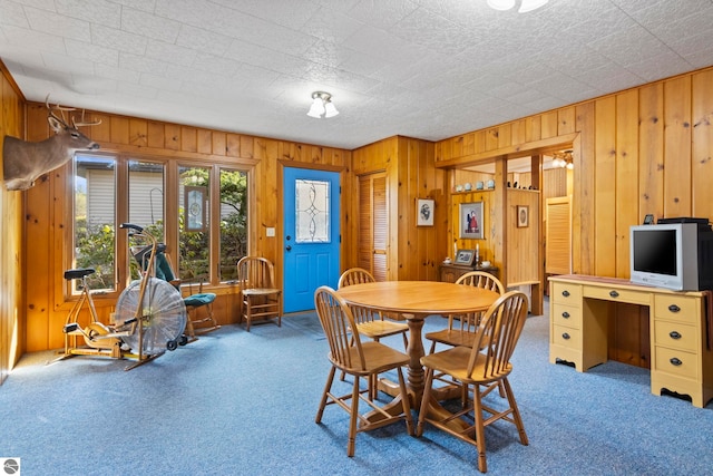 carpeted dining area featuring wooden walls