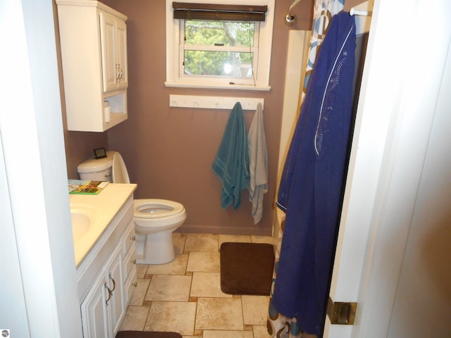 full bath with toilet, baseboards, stone finish floor, and vanity