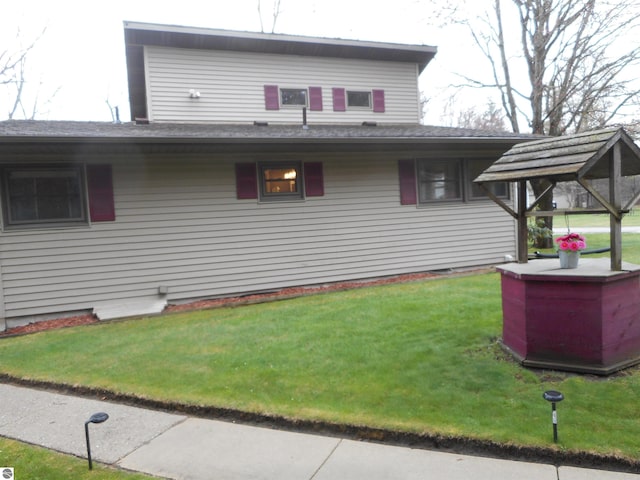 view of side of property featuring a lawn and a shingled roof