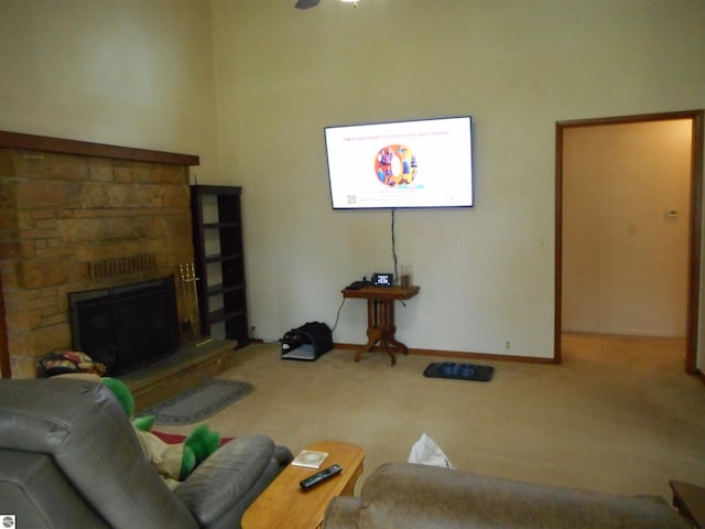 carpeted living area featuring baseboards, a ceiling fan, and a stone fireplace