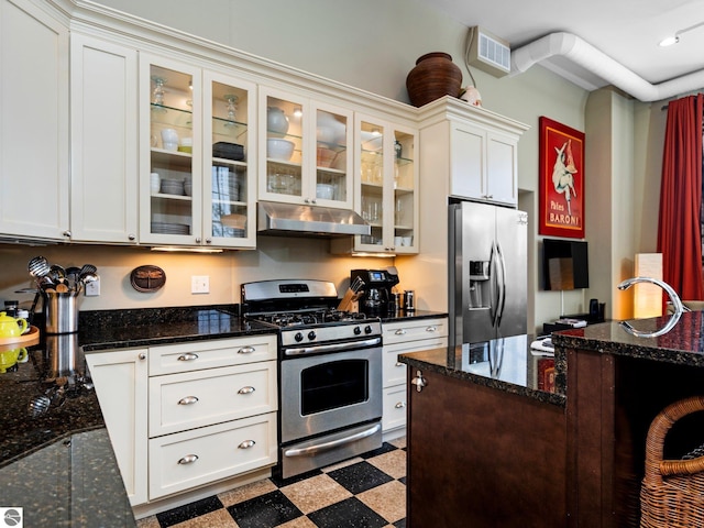 kitchen featuring appliances with stainless steel finishes, tile patterned floors, white cabinetry, under cabinet range hood, and glass insert cabinets