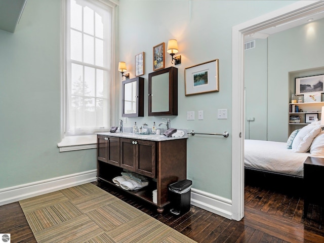 ensuite bathroom with wood-type flooring, visible vents, vanity, baseboards, and ensuite bathroom