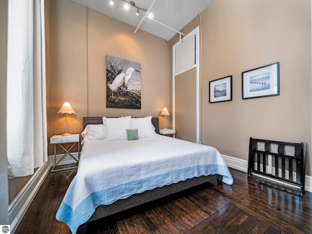 bedroom with baseboards, wood-type flooring, and rail lighting