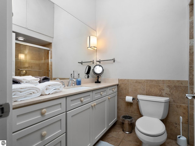 bathroom featuring tile patterned flooring, vanity, toilet, tile walls, and a stall shower
