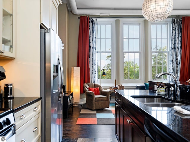 kitchen with dark wood-style flooring, a sink, stainless steel fridge with ice dispenser, dishwasher, and glass insert cabinets