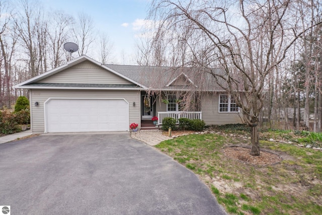 ranch-style house featuring roof with shingles, an attached garage, a porch, and driveway
