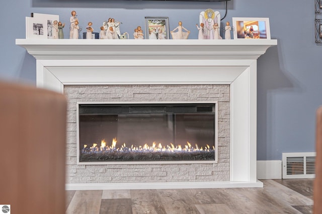 interior details featuring visible vents, a glass covered fireplace, and wood finished floors