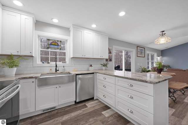 kitchen with visible vents, appliances with stainless steel finishes, a sink, white cabinets, and a peninsula