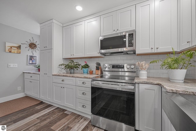 kitchen with white cabinets, appliances with stainless steel finishes, baseboards, tasteful backsplash, and dark wood-type flooring